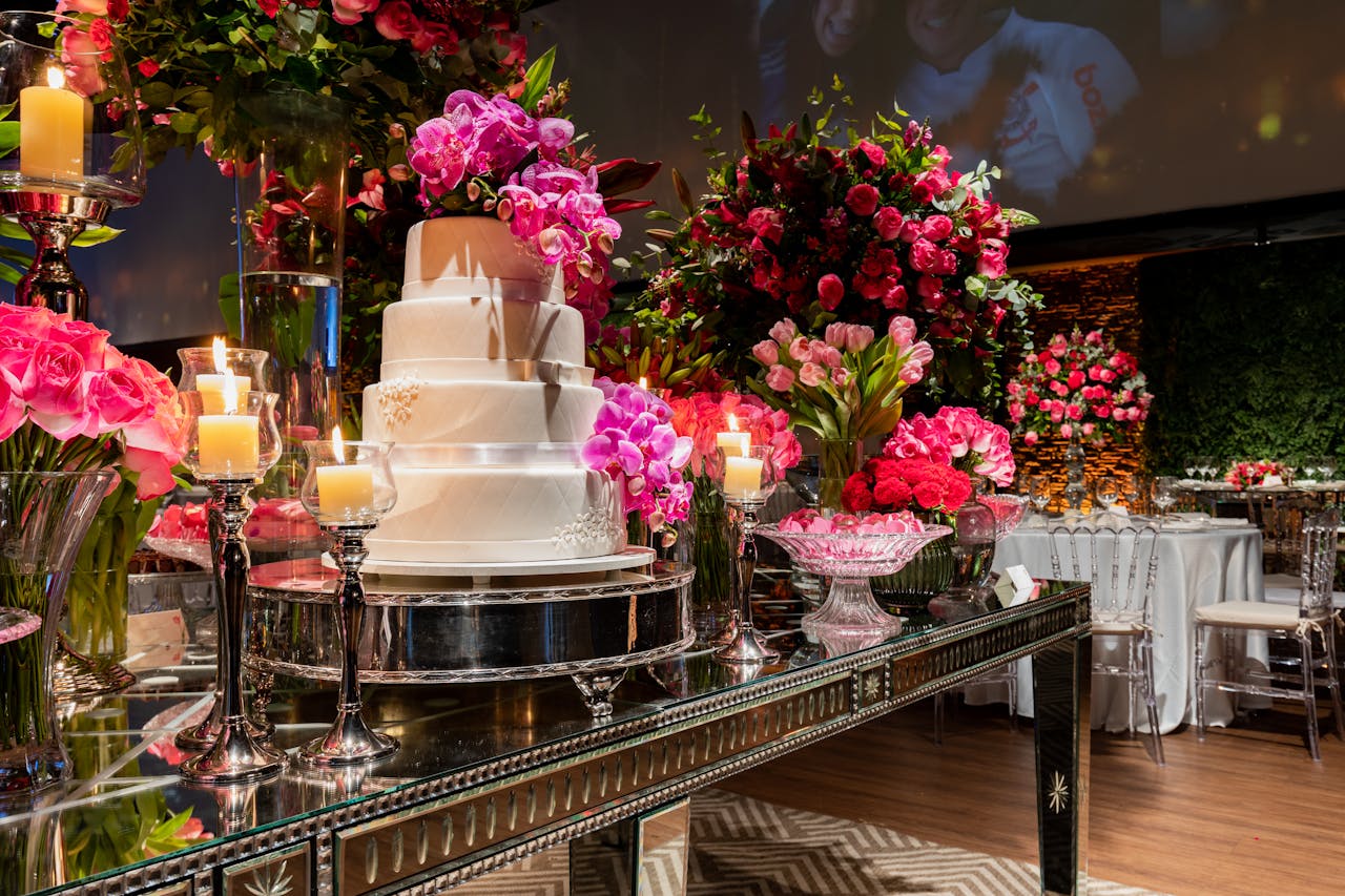 A beautifully decorated wedding reception featuring an elegant cake surrounded by vibrant floral arrangements and candles.